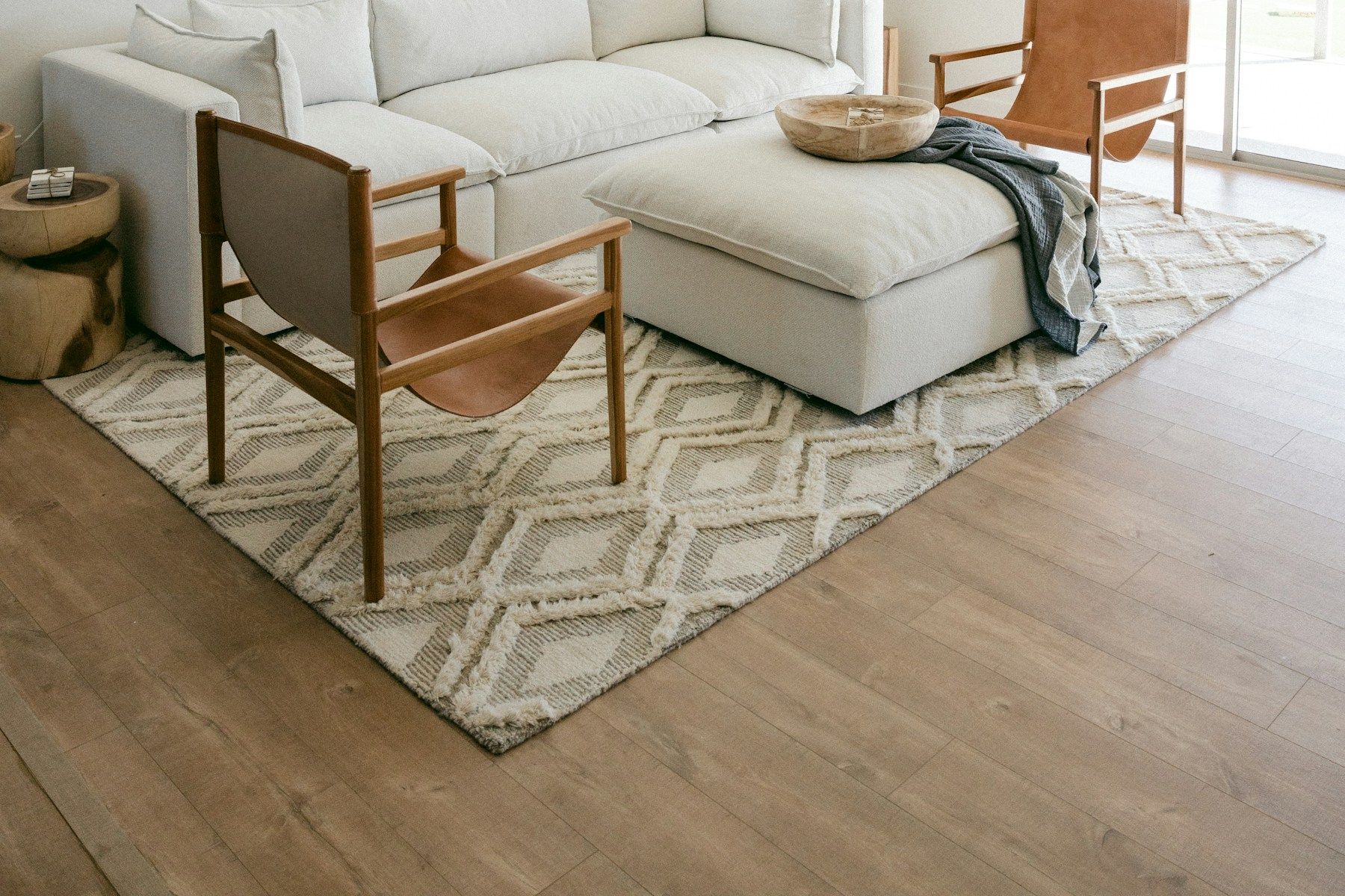 Salón con sofá claro, butacas de madera y luz natural