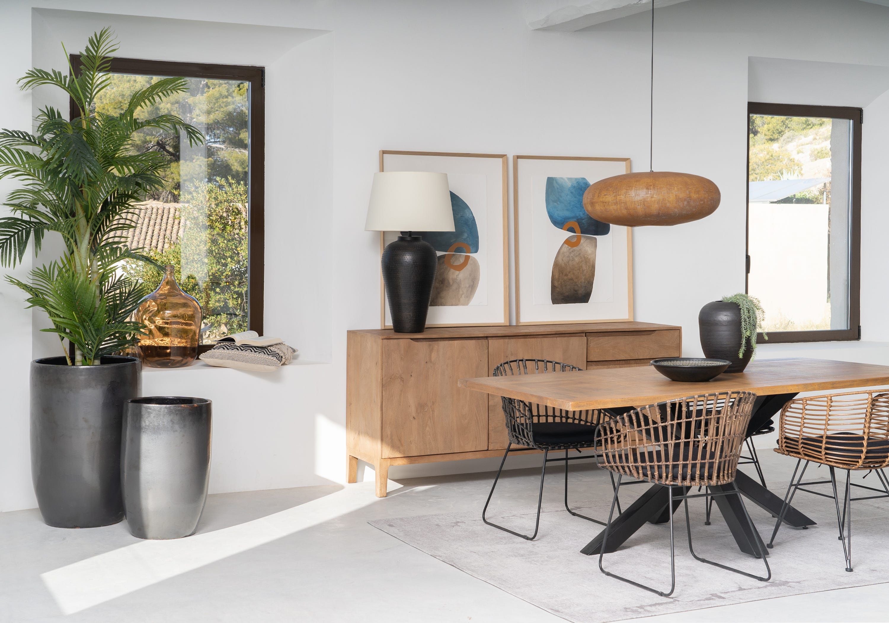 Comedor con mesa de madera, sillas de fibra, aparador y plantas junto a dos ventanas